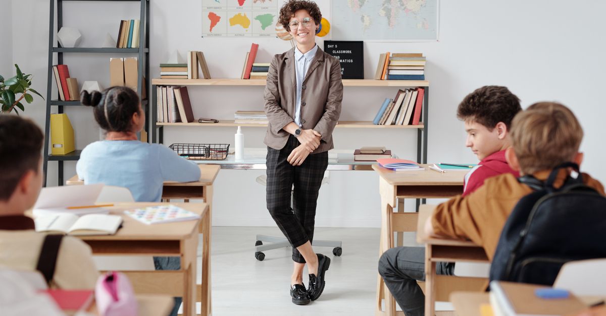 Teacher engaging with diverse students in a modern classroom setting for education.