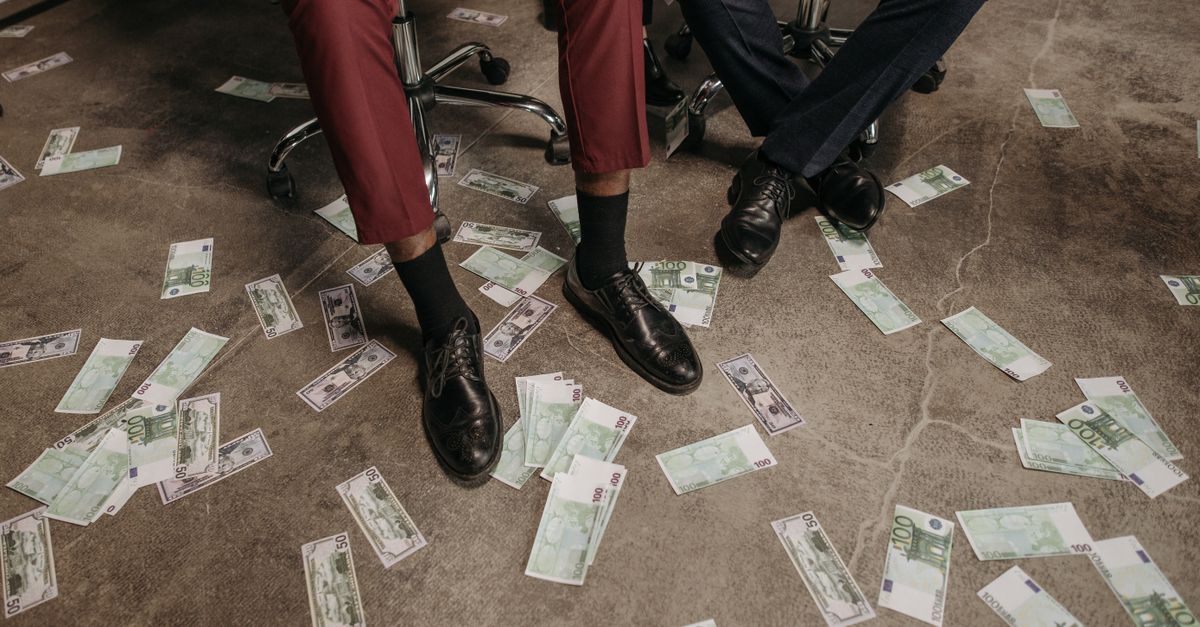 Two people in an office with euro banknotes scattered on the floor, showcasing a financial theme.
