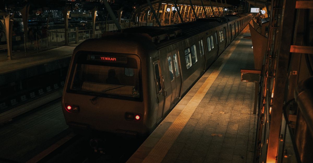 A tranquil night scene capturing a metro train at a station in Istanbul, with city lights in the background.
