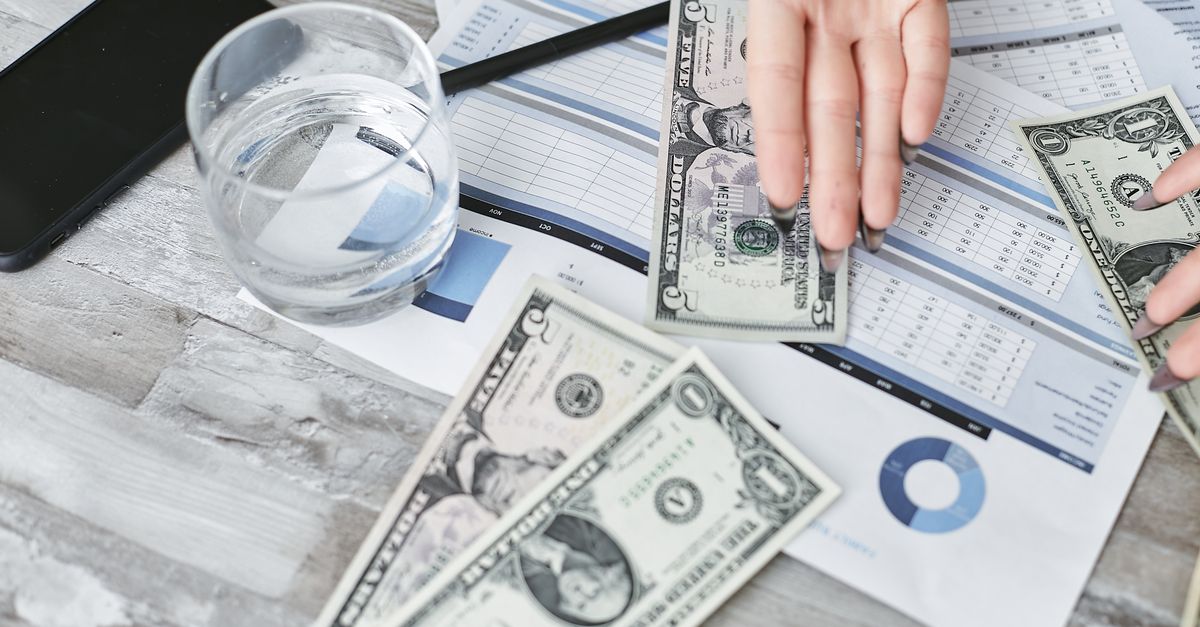 A top view of financial documents with dollar bills and a glass of water, emphasizing budgeting.