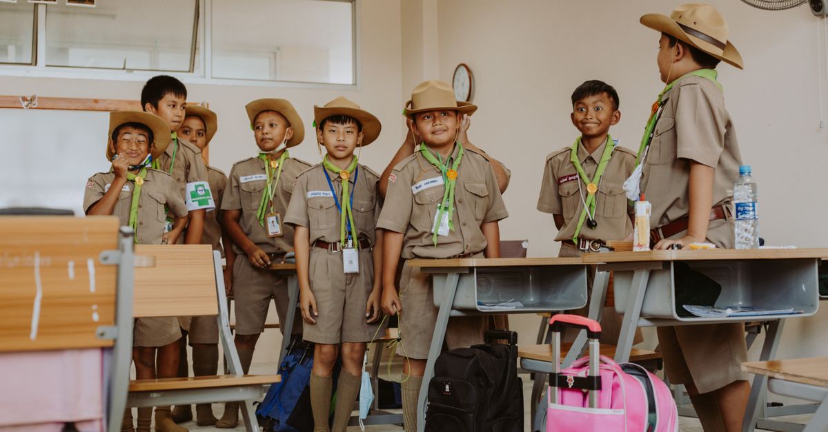 Boy scouts in uniform having fun in a classroom, showcasing education and teamwork.