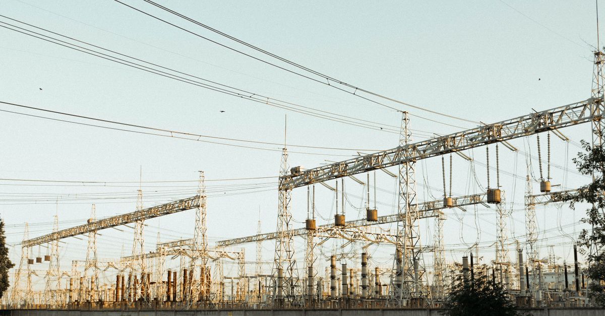 A wide view of an industrial electrical substation with power lines and towers outdoors.