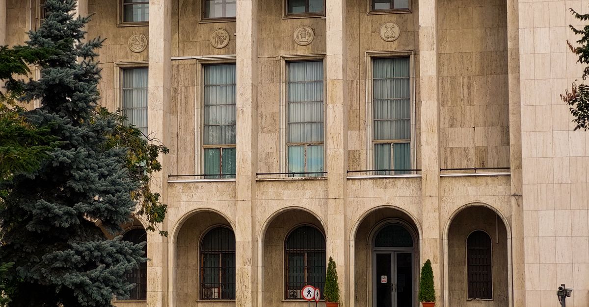 Exterior of a classical building with columns, arches, and greenery, showcasing elegant architecture.