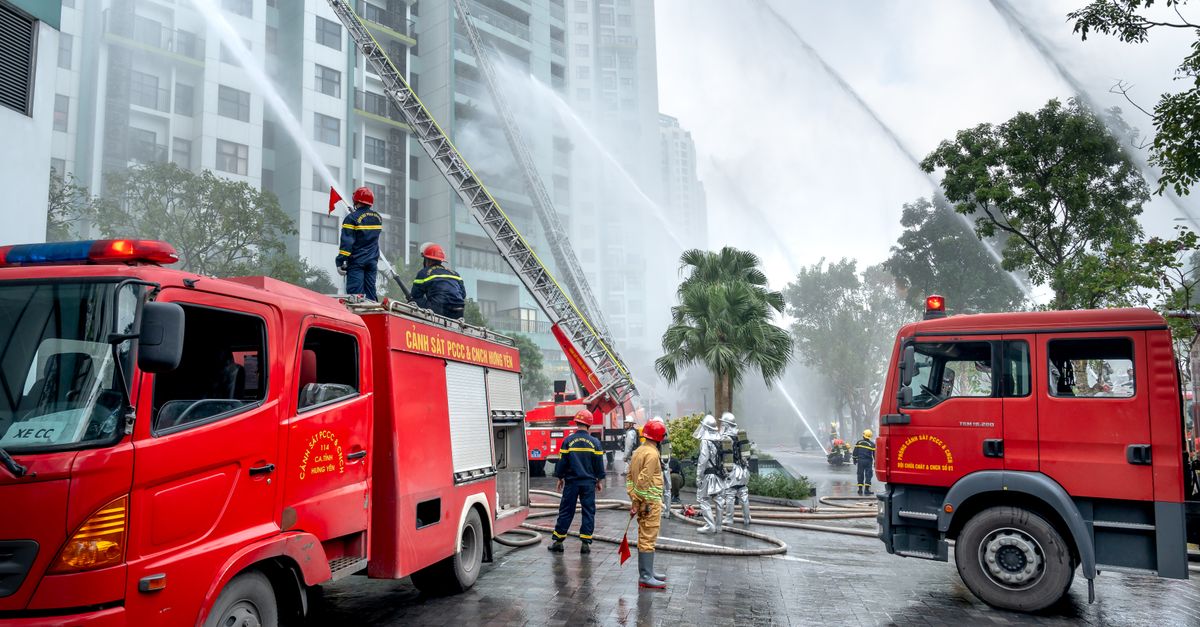 Firefighters and trucks in an urban setting battling a fire, using hoses to control the blaze.