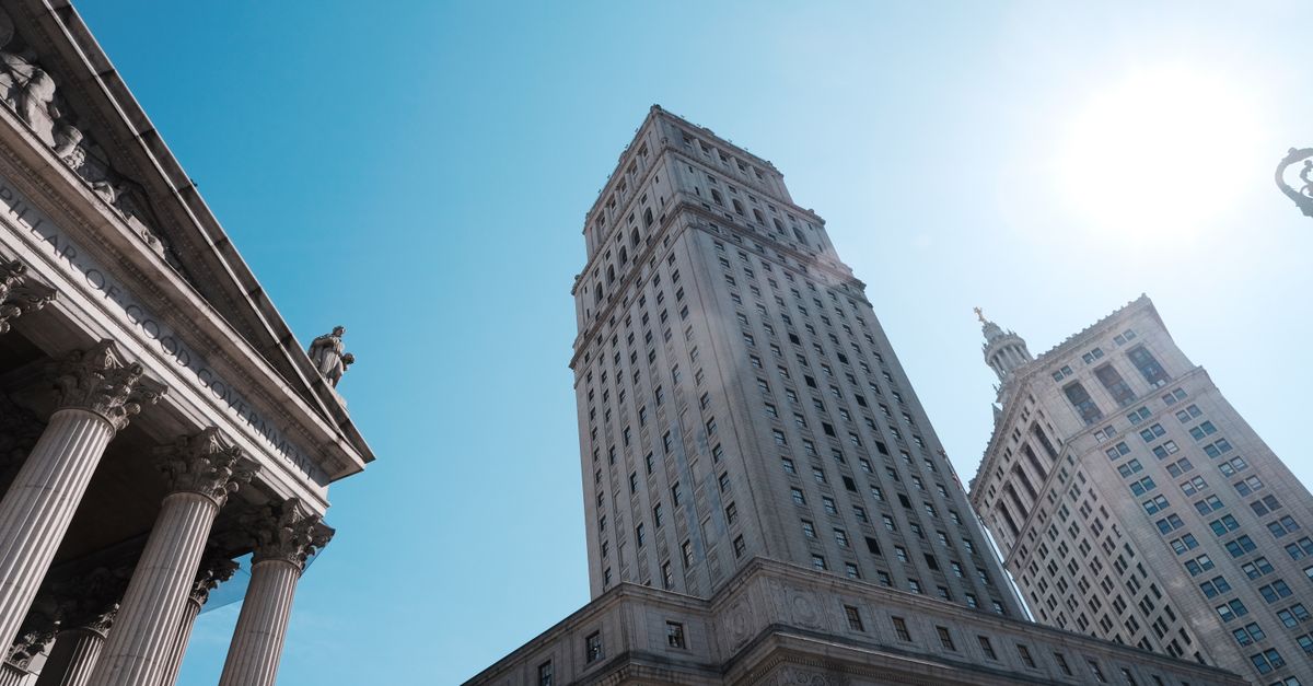 Elevated view of towering skyscrapers and historic architecture against a clear blue sky.