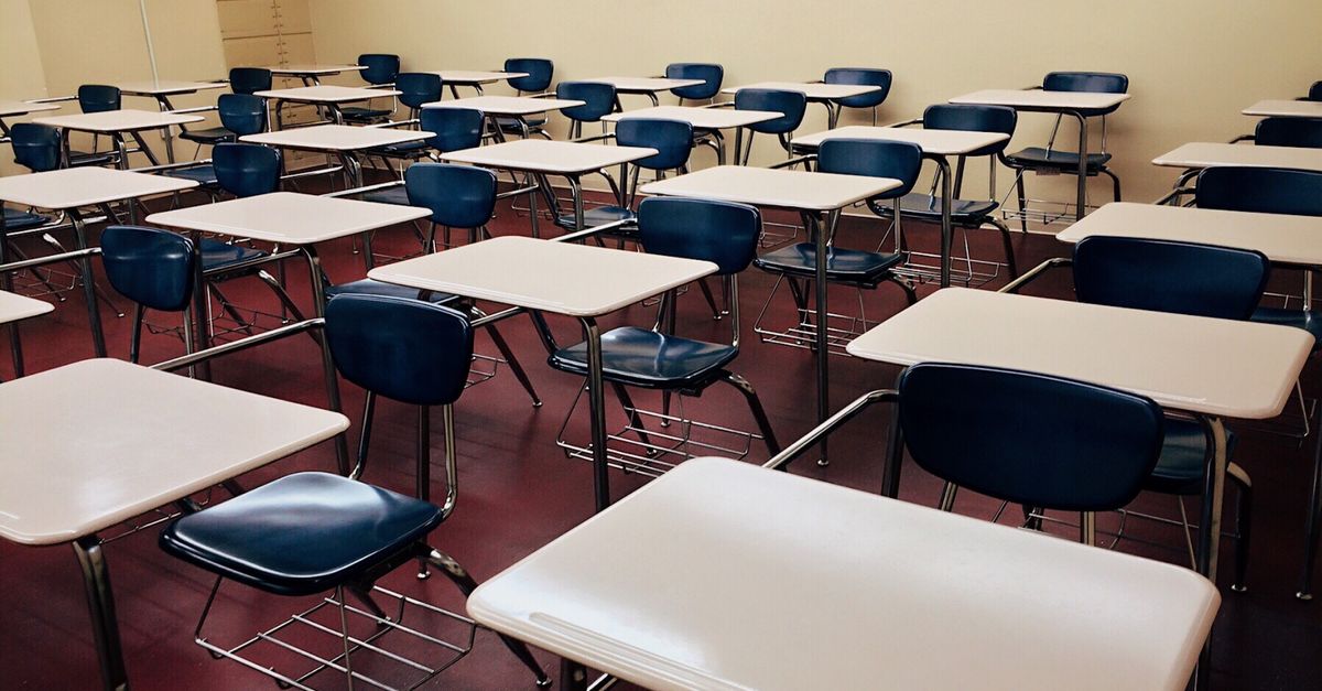 An empty classroom featuring neatly arranged desks and chairs ready for use.