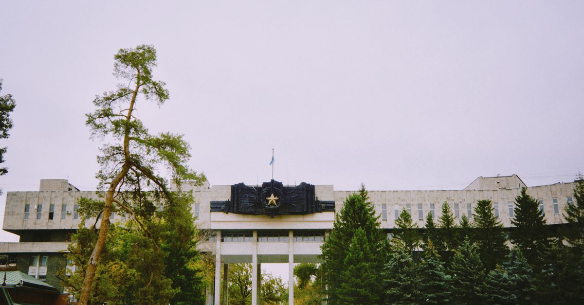 Outdoor view of a government building surrounded by trees in Almaty, Kazakhstan.