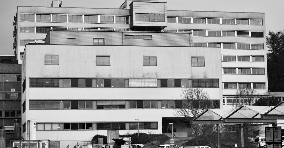 Black and white photo of an industrial office building facade with parked cars.