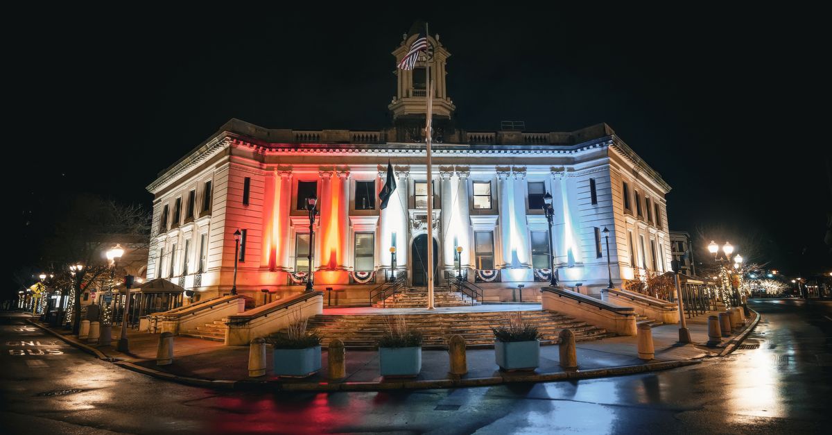 A beautifully lit historic courthouse building with red, white, and blue lights reflecting patriotism.