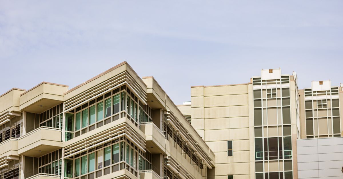 A modern building with angular glass facade against the clear sky.