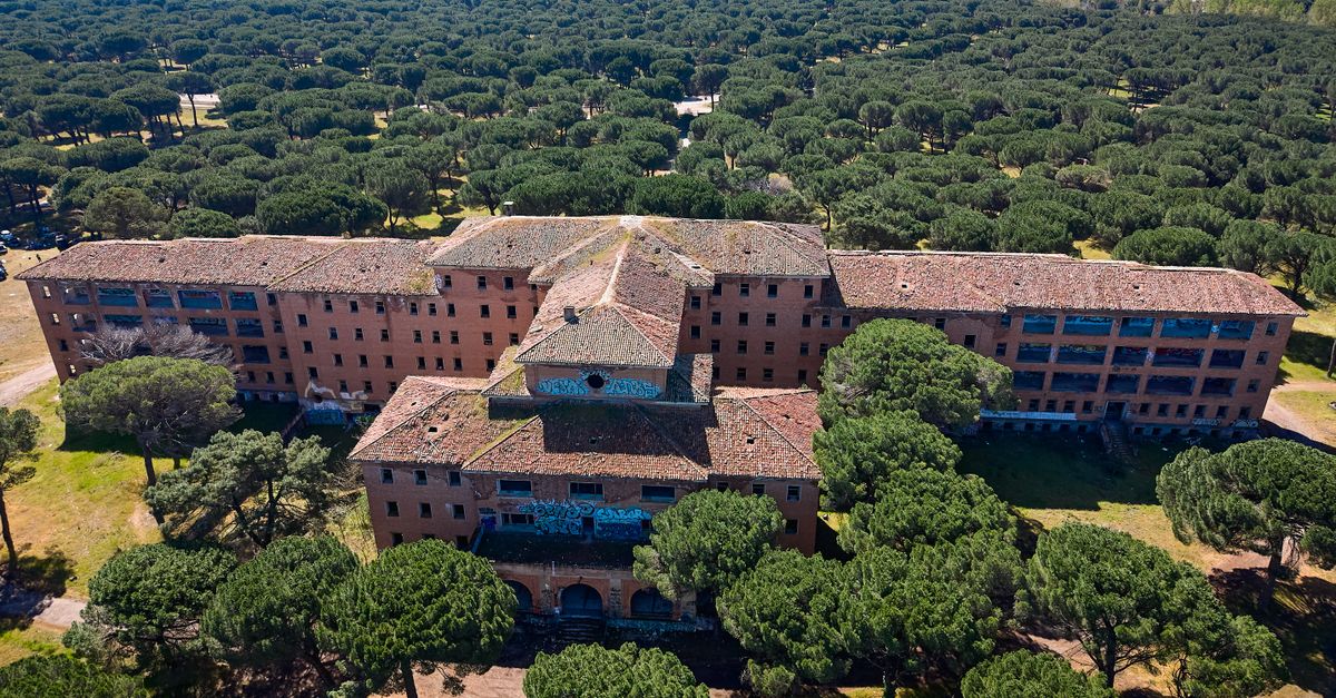 Drone shot of abandoned hospital in Valladolid, surrounded by lush green forest.