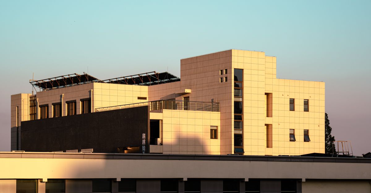 Contemporary building highlighted by sunset, featuring solar panels and urban design.