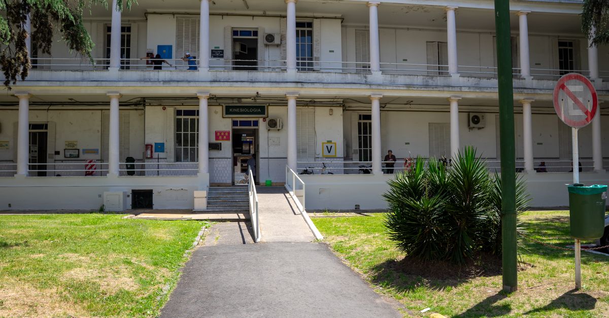 Exterior view of a historic building with columns, surrounded by greenery and a clear sky.