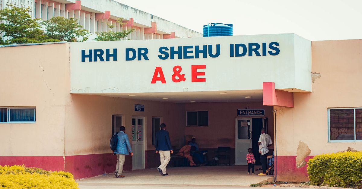 Visitors entering HRH Dr Shehu Idris A&E, capturing outdoor hospital scene with people.