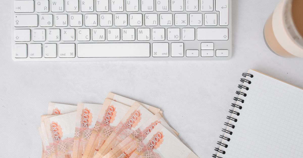Russian banknotes with a keyboard and notebook on a white table surface, ideal for business finance themes.