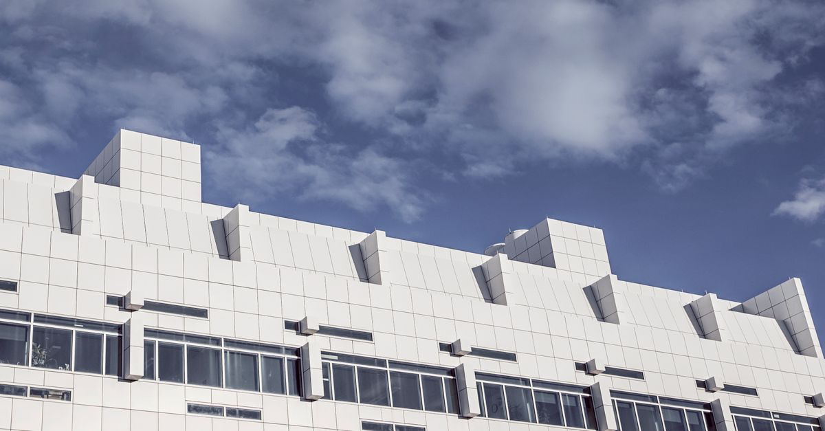 A sleek, modern white building with modular design set against a partly cloudy sky.