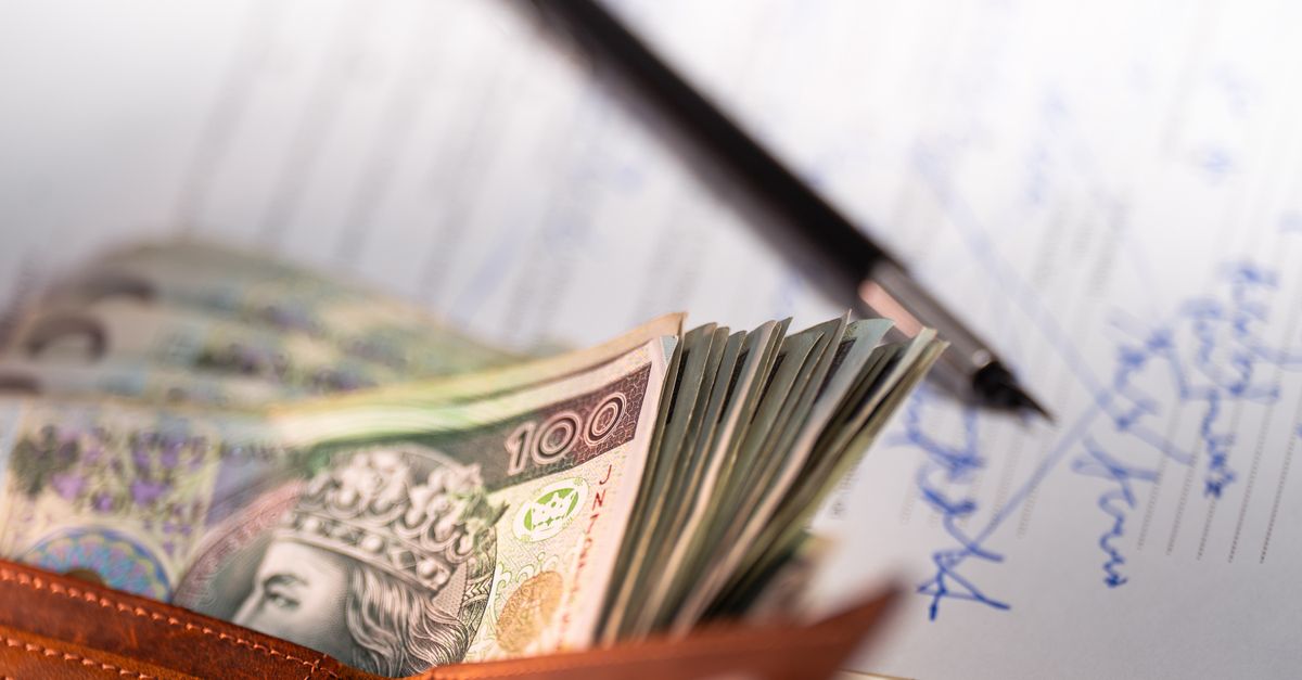 Stack of Polish zloty banknotes with pen and document, financial concept.