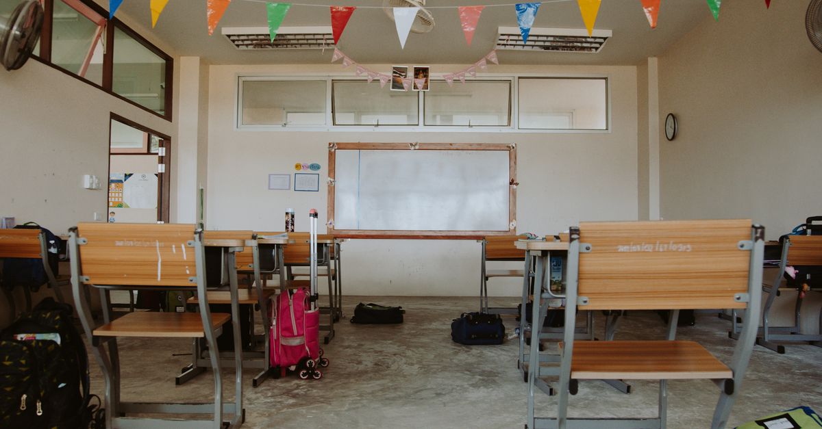 An empty classroom setup with desks and colorful banners, indicating a school setting.