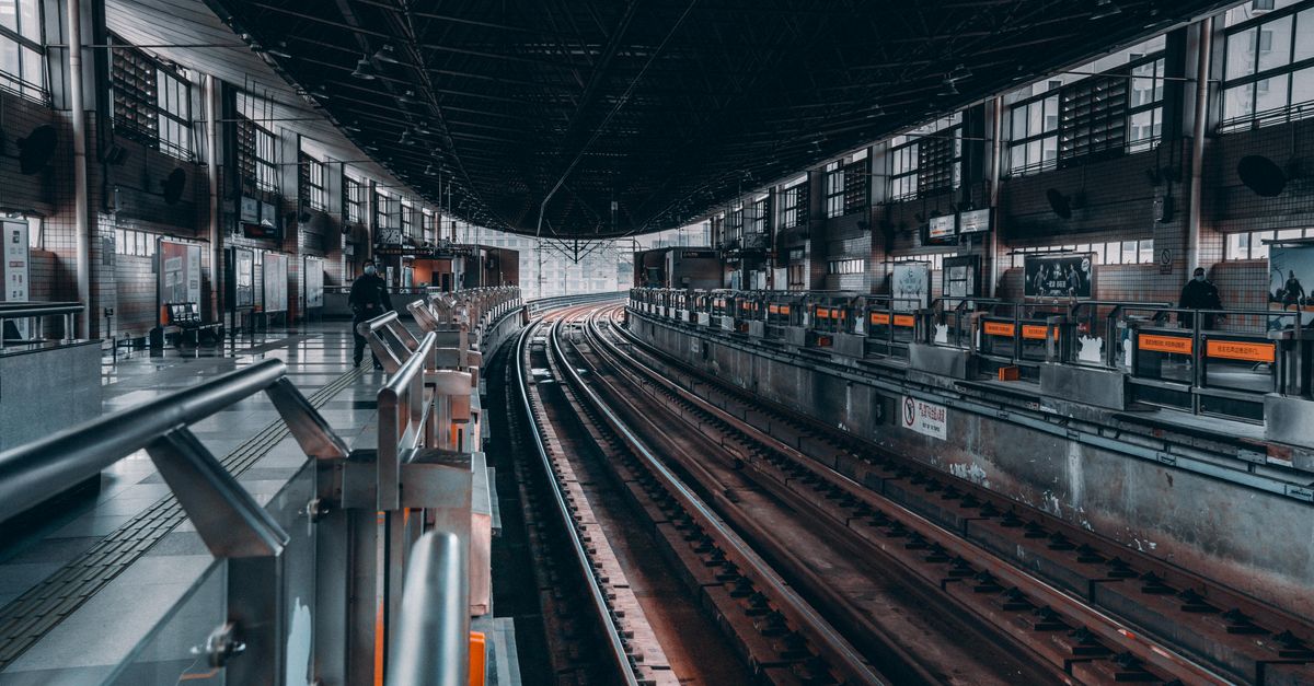 Modern railway station interior showing tracks and platforms in an urban setting.