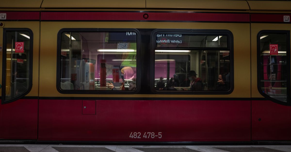 Passengers seen through a modern train window at an indoor station.