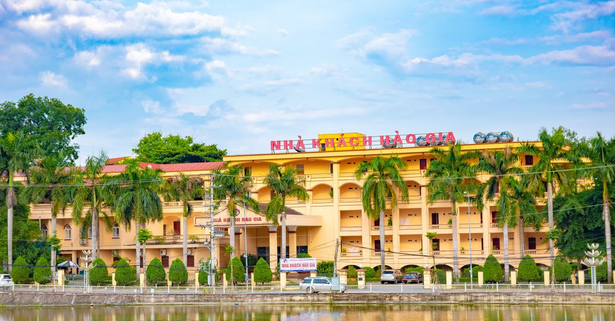 Charming hotel building with palm trees and pond reflection, ideal for travelers in Vietnam.