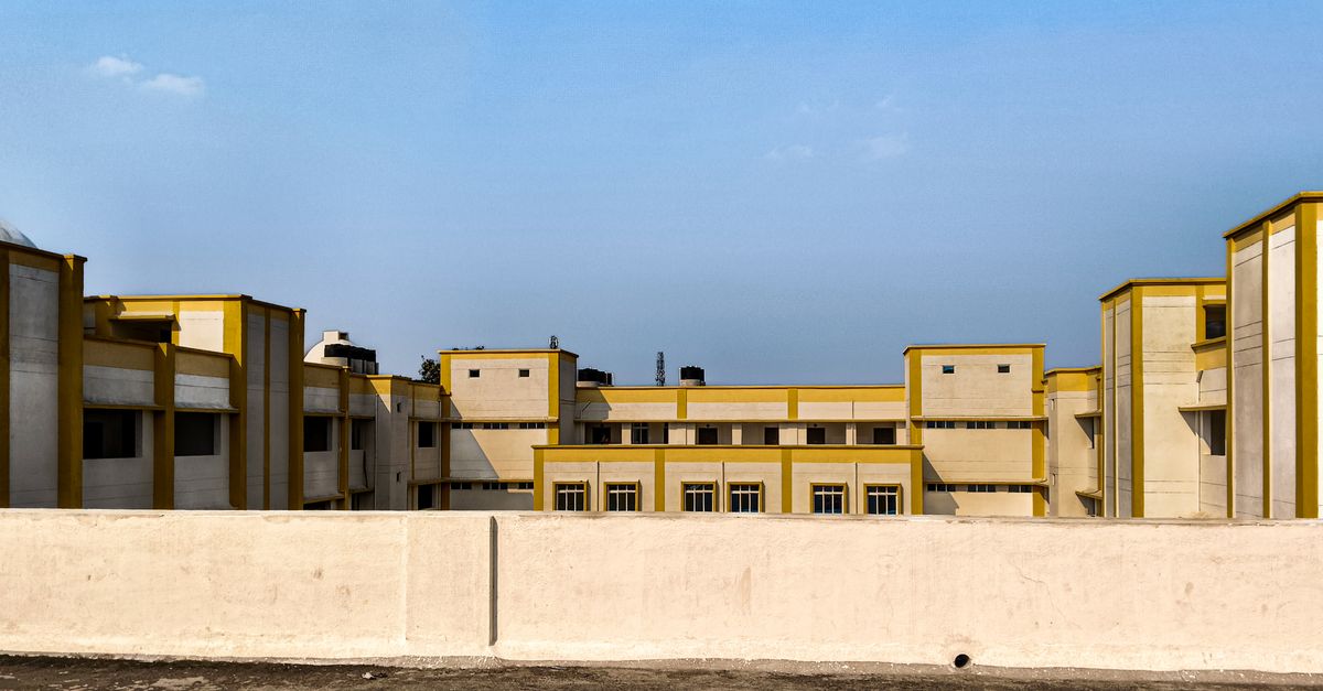 Contemporary building with geometric design in warm sunlight, set against a clear blue sky.