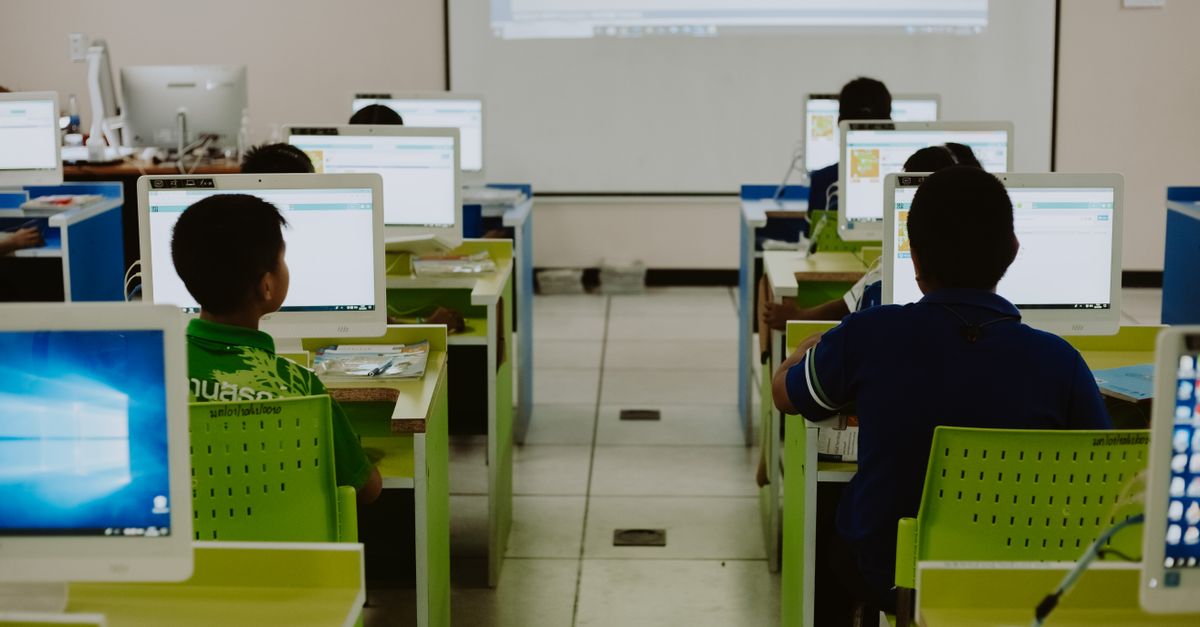 Children focus on computers in a modern classroom setting.