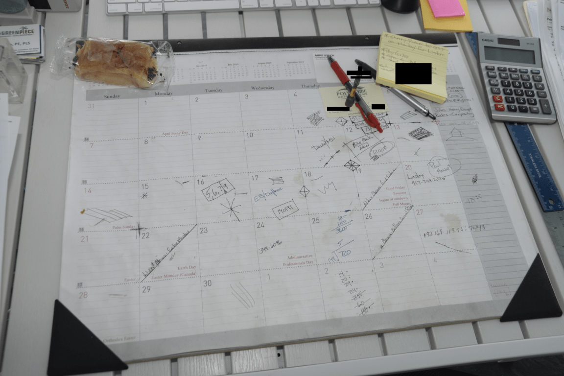 A desk with a calendar, notes and a calculator